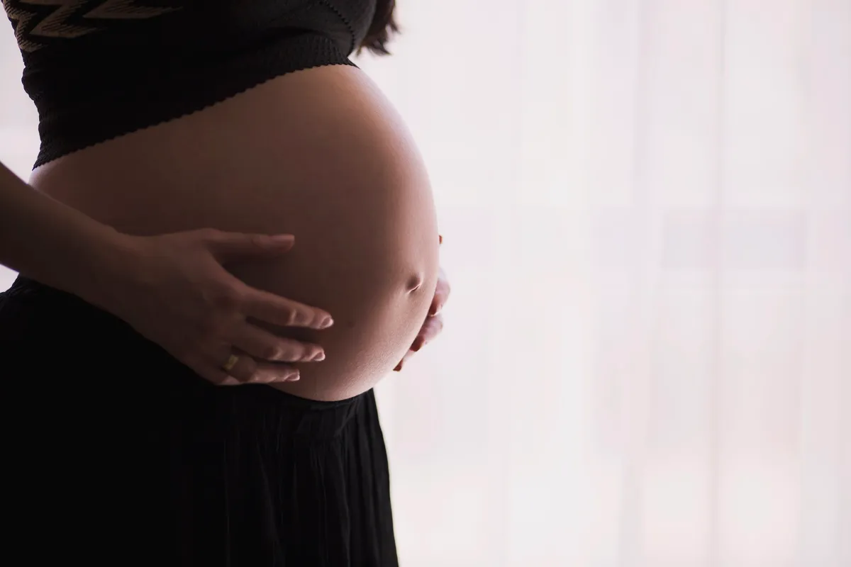 A pregnant woman cradling her belly in soft light